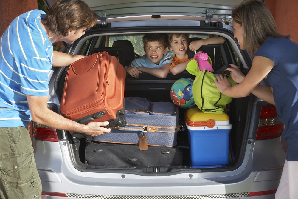 Two,Young,Sons,Watching,Parents,Load,Luggage,In,Car,Trunk